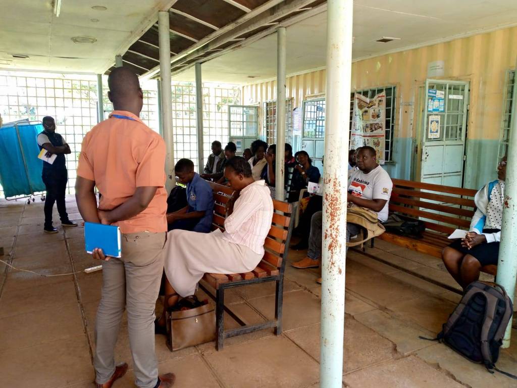 Group of people sitting down while listening to two people standing speaking.